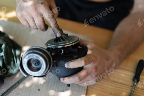 Preview: A man repairs a car part on the table