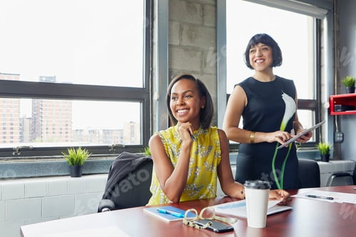 Preview: Two women in office, looking away, smiling