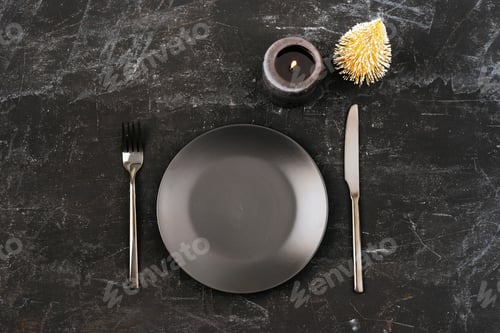 Preview: Stylish table setting with black plate, cutlery, toy fir tree and candle on black table.