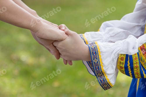 Preview: Woman's hand holding a baby hand close up. Ukrainian national clothes, Ukraine. No war