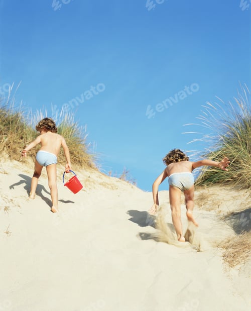 Preview: Twins running up a sand dune
