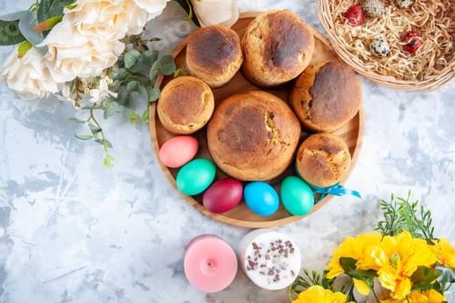 Preview: top view colored easter eggs with holiday bread and cakes inside tray on white background concept