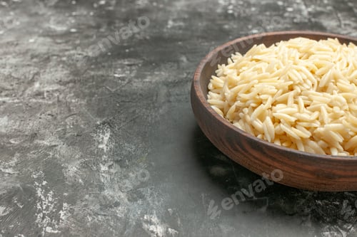 Preview: Half shot of boiled rice in a brown wooden pot on the right side on dark background