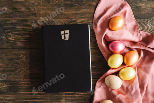 Preview: Multicolored Easter eggs and holy bible on a wooden background. Religion concepts