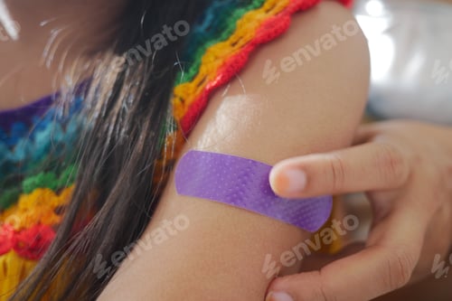 Preview: Child applying a band-aid on her arm after a minor scrape