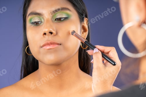Preview: Applying highlighter on the cheeks of a young woman