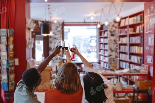 Preview: Friends toasting with red wine in bookstore: celebrating literature and friendship