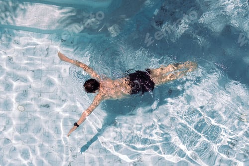 Preview: Young man swimming freestyle in a pristine rooftop pool