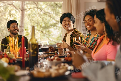 Preview: Group of happy young friends is drinking wine while having holiday dinner home party together