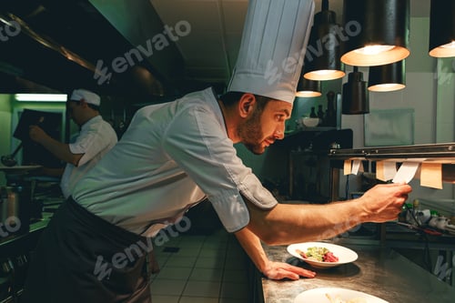 Preview: Handsome Chef cook in uniform checking the order at the restaurant kitchen