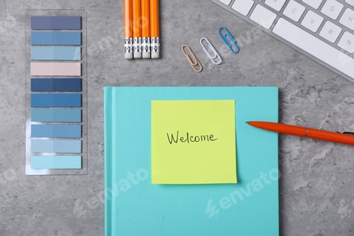 Preview: Sticky note with word Welcome, stationery and keyboard on grey table, flat lay