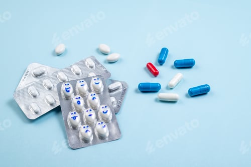 Preview: Blister of funny pills with smiles faces on blue background. Health care, daily pills
