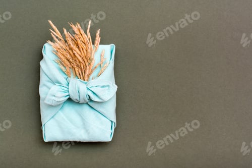 Preview: Eco friendly furoshiki gift with ears of dry grass on green background