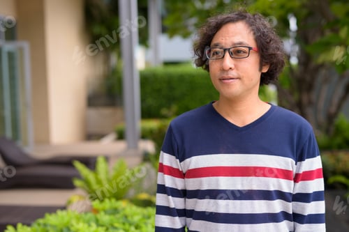Preview: Portrait of Japanese man with curly hair thinking in the rooftop garden