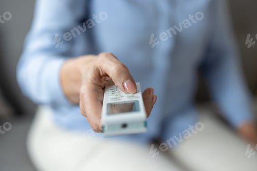 Preview: Person adjusting an air conditioner remote control