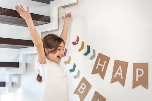 Preview: Preparation for the birthday. Girl hangs Happy Birthday sign on a wall.