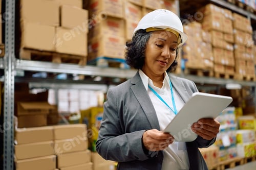 Preview: Mature businesswoman using digital tablet while working in a distribution warehouse