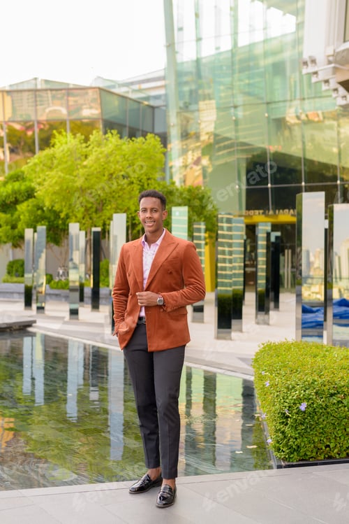Preview: Happy African businessman outdoors in city smiling full length shot