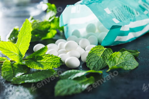 Preview: Mint candies. Menthol bonbons and mint leaves on black table.