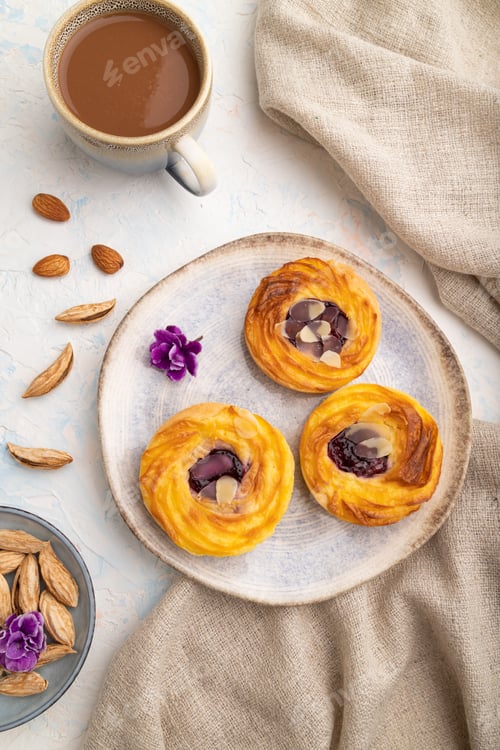 Preview: Small cheesecakes with jam and almonds with cup of coffee on a white concrete background