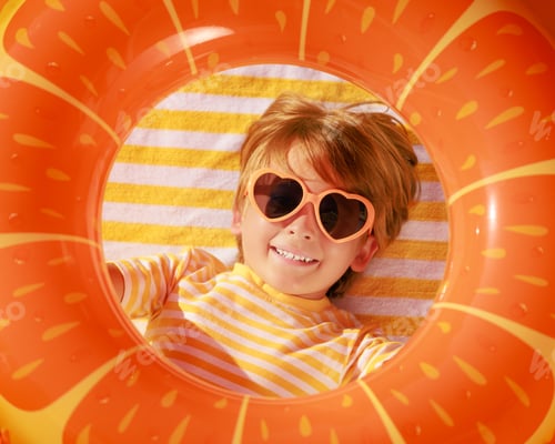 Preview: Top view portrait of happy child lying on beach towel on summer vacation