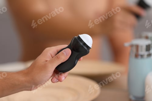Preview: Young man holding deodorant in bathroom, closeup