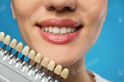 Preview: Woman checking her teeth color on blue background, closeup. Cosmetic dentistry