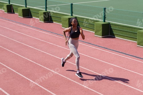 Preview: Sportive African American woman runs on red track around stadium to prepare for upcoming marathon