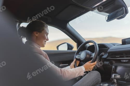 Preview: Excited young woman driving her electric car.