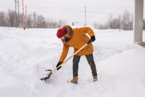 Preview: Man removing snow and ice from the sidewalk in front of house. Winter season