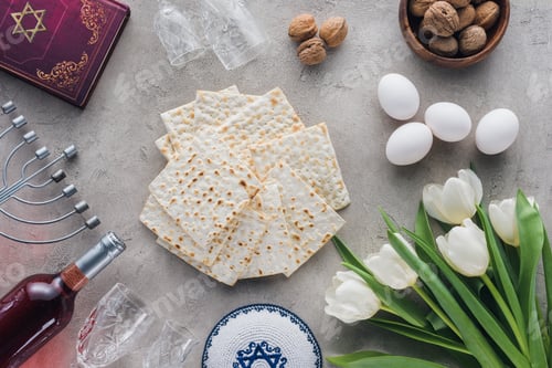 Preview: top view of traditional book with text in hebrew, matza and menorah on concrete table