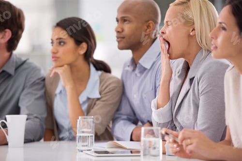 Preview: Shot of a businesswoman yawning during a meeting with her colleagues
