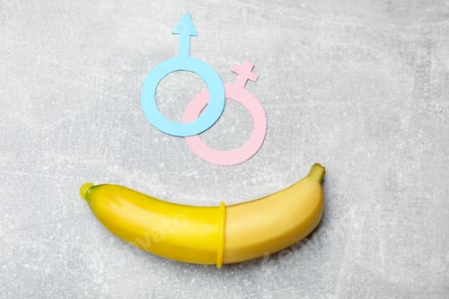 Preview: Sex education. Banana with condom and gender symbols on grey table, flat lay