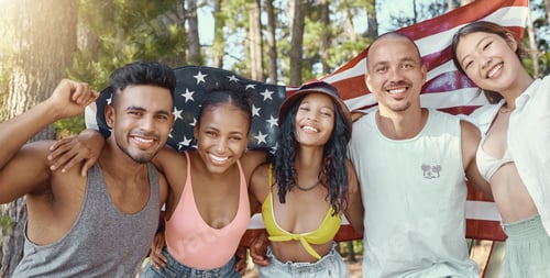 Preview: Shot of a diverse group of friends standing and holding the American flag during a day in the woods