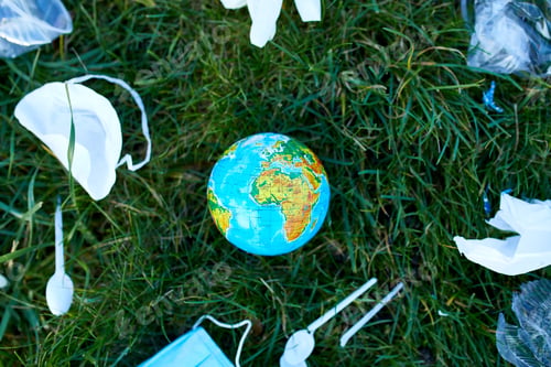 Preview: A globe in a pile of scattered garbage on a background of green grass