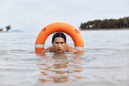 Preview: Summer Lifesaver: Asian Lifeguard on Duty, Safeguarding the Beach with Lifebuoy in Blue Waters