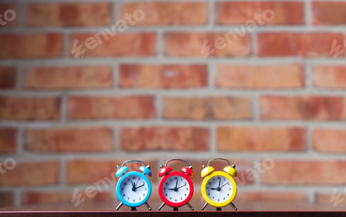 Preview: Three little red alarm clocks on table