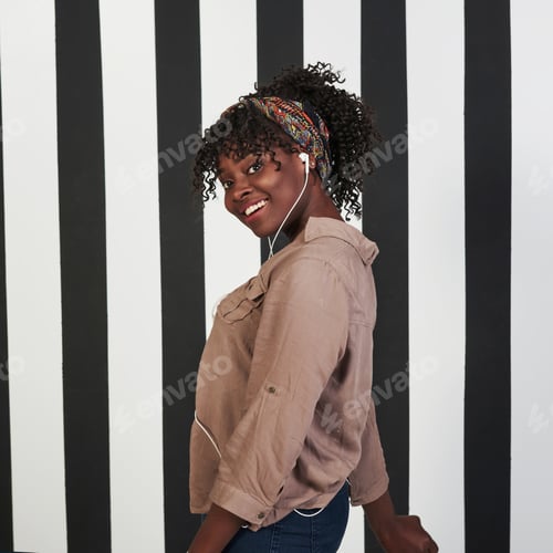 Preview: Smiled afro american girl stands in the studio with vertical white and black lines at background