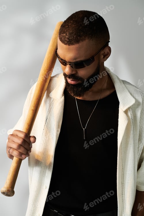 Preview: Stylish handsome man posing with a baseball bat in a modern urban setting during daylight hours