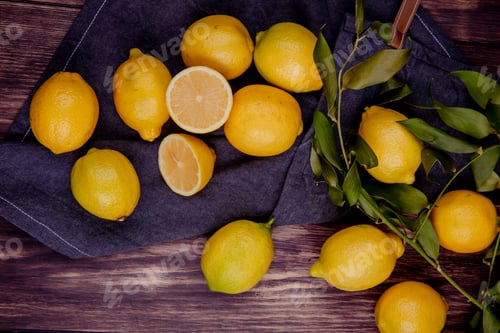 Preview: top view of fresh ripe lemons on black fabric on rustic background
