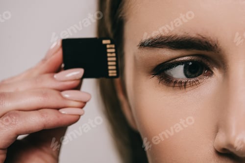 Preview: cropped view of microchip near eye in hand of woman