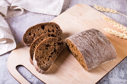 Preview: Italian rye ciabatta bread sliced on a wooden board on the table.