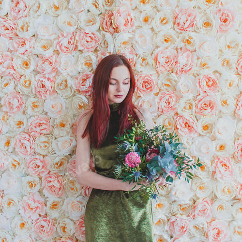 Preview: Woman Holds Flowers in Front of Flower Wall
