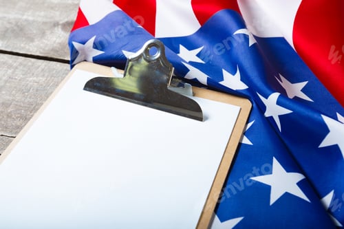 Preview: blank clip board and USA flag on wooden background