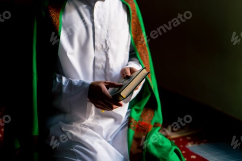Preview: Islamic prayer concept Close-up of a Muslim man sitting on his knees praying with the Holy Quran