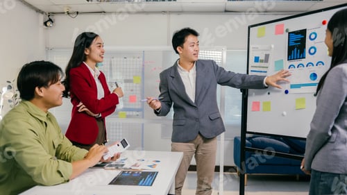 Preview: Asian business team analyzing charts and statistics on whiteboard during office meeting