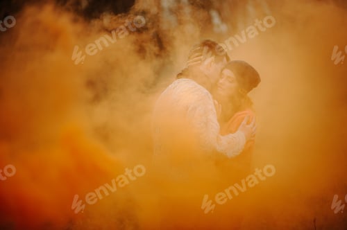 Preview: Young happy couple holding smoke bombs on camping