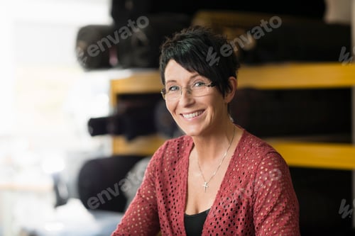 Preview: Portrait of mature seamstress in front of textile rolls in workshop