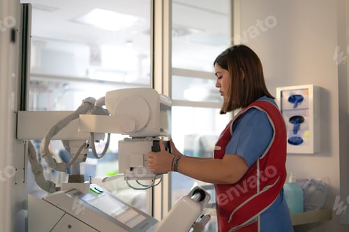 Preview: Female nurse preparing portable x-ray machine in hospital room