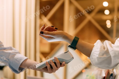 Preview: Side view of a female customer paying for her cost with a smart watch.